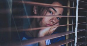 A girl looks out a window and wonders how she can stop spending more than she makes.